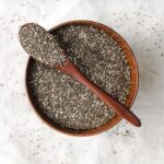 A spoonful of premium chia seeds with wooden background – healthy superfood by Pyazon