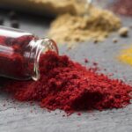 Paprika powder in a bowl with wooden spoon and scattered red pepper flakes – Pyazon spice collection