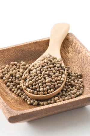 Dried sabut dhaniya seeds in a rustic bowl on a wooden table