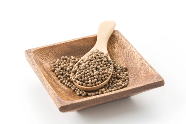 Dried sabut dhaniya seeds in a rustic bowl on a wooden table
